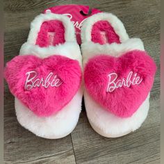 a pair of pink and white slippers with the word barbie written on them