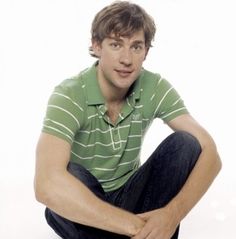 a young man sitting on the ground with his legs crossed and looking at the camera