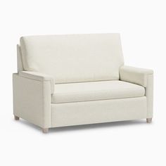 a white couch sitting on top of a white floor next to a wooden frame chair