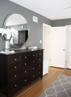 a bedroom with a dresser, mirror and flowers on it