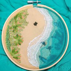 an embroidered beach scene is shown on a turquoise background, with the ocean and shore visible