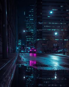 a city street at night with cars parked in the rain