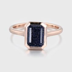 a rose gold ring with a blue druzby stone in the center, on a white background