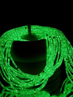 a green rope is lit up in the dark with its end turned to look like it's glowing