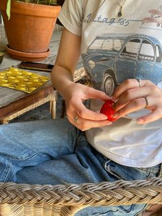 a person sitting on a chair with a red object in their hand and a potted plant behind them