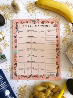 a meal planner surrounded by fruits and other foods on a white table with gold flakes