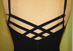 the back of a woman's black leotard with straps and metal studs