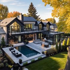 an aerial view of a house with a swimming pool in the foreground and landscaping around it