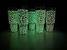 four cups are lit up in the dark with green and red designs on them,