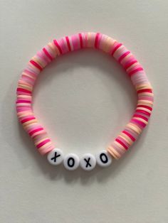 a pink and white beaded bracelet with the word xoxo spelled on it