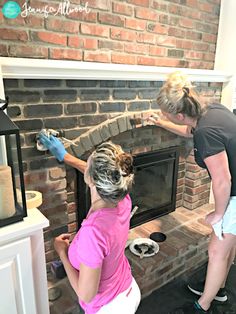 two women are painting a brick fireplace in the living room