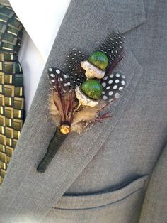 a boutonniere decorated with feathers and other things is sitting on the lapel of a man in a suit