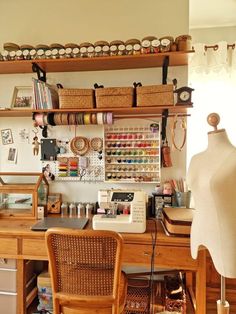 a sewing studio with lots of crafting supplies on the desk and shelves above it