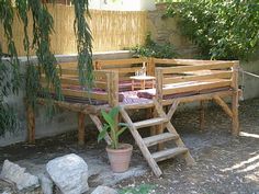 a wooden bench sitting under a tree next to a plant potted in front of it