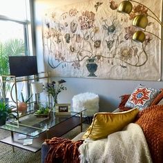 a living room filled with furniture and a large painting on the wall above it's glass coffee table