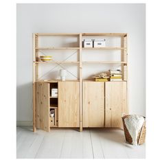 a wooden bookcase with shelves and baskets on the floor in front of a white wall