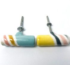 two colorful ceramic earrings with metal hooks on each side, one is white and the other is