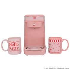 a pink coffee maker with two mugs and a hello kitty mug next to it