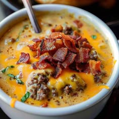 a close up of a bowl of soup with bacon and cheese in it on a table