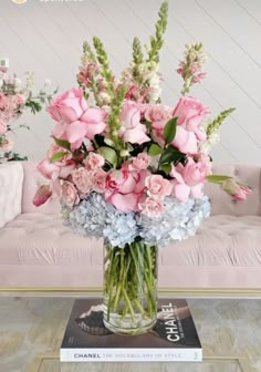 a vase filled with pink and blue flowers sitting on top of a table next to a couch