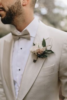 a man wearing a white suit and flower boutonniere