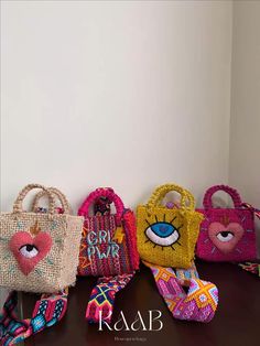 four bags with different designs on them sitting on a table next to a white wall