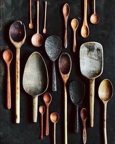 wooden spoons are lined up on a black surface with different shapes and sizes in them