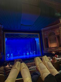 people sitting in front of a stage with their feet on the ground looking at it