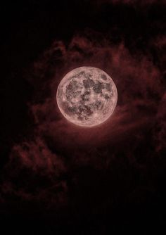 the full moon is seen through clouds in this dark night time photo, with red hues