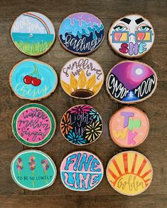 twelve decorated cookies are arranged on a wooden surface with the wording painted on them