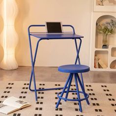 a blue desk with a laptop on it and a stool next to it in a living room