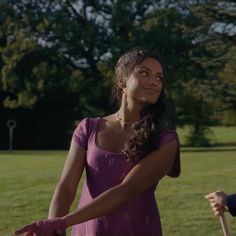 a woman in a purple dress holding a pink frisbee while standing next to another person