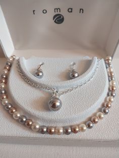 "Roman brand jewelry set consists of two beautiful necklaces and one pair of matching earrings.  First necklace is a faux gray pearl bead. Rhinestone crown and hung on a 18\" silver tone chain. Second necklace is a variety of small pearl like beads in shades of cream, brown and gray. 16\". Post earrings are drop style. Single gray bead with a silver rhinestone crown. Silver ear wires. Never worn, comes in original gift box. Smoke free home." Crown Silver, Pearl Necklace Set, Rhinestone Crown, Grey Beads, Brand Jewelry, Pearl Grey, Silver Rhinestone, Original Gift, Jewelry Branding