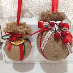 two burlocked ornaments with red bows and berries on them are sitting in a box