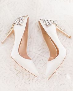 a pair of white wedding shoes with jeweled details on the toes and heels are laying on a lace covered surface