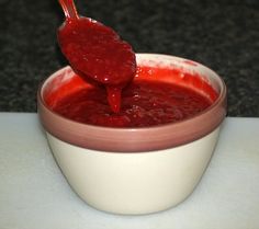 a spoon is pouring red sauce into a bowl