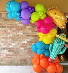 a bunch of balloons that are in the shape of a rainbow with a smiley face on it