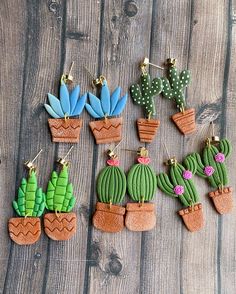 small cactus and succulents are hanging from hooks on a wooden surface,