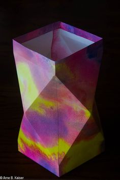 an origami box that looks like it is made out of paper and has been painted with different colors