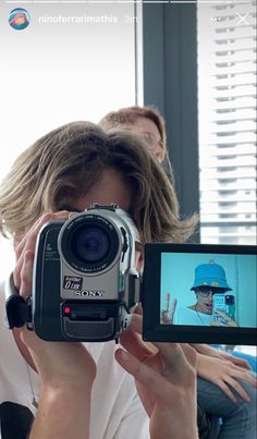 a man holding up a camera to take a picture with another person in the background