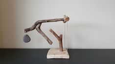 a sculpture made out of driftwood with a stone hanging from it