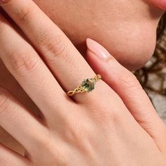 a close up of a person's hand with a ring on their finger and an emerald stone in the middle