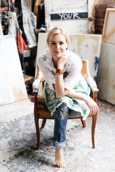 a woman sitting in a chair with her hand on her chin and looking at the camera