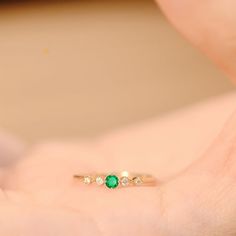 a woman's hand holding an emerald and diamond ring