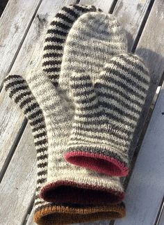 a pair of mittens sitting on top of a wooden table next to a cup