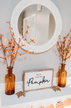 there are three vases with flowers in them on the mantle next to a mirror