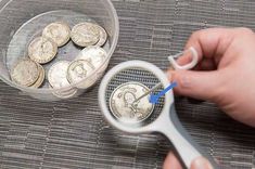 a person holding a magnifying glass with some coins in it and looking at them