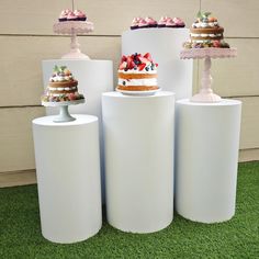 there are four cakes on top of three large cylinders, each with different toppings