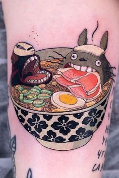 a tattoo with an image of totoro and ramen in a bowl on the leg