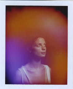 a polaroid photograph of a woman's face and shoulders in front of an orange background